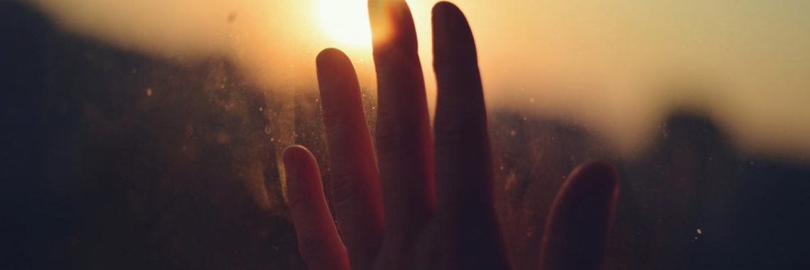 Hand reaching for the sunset, full of hope.
